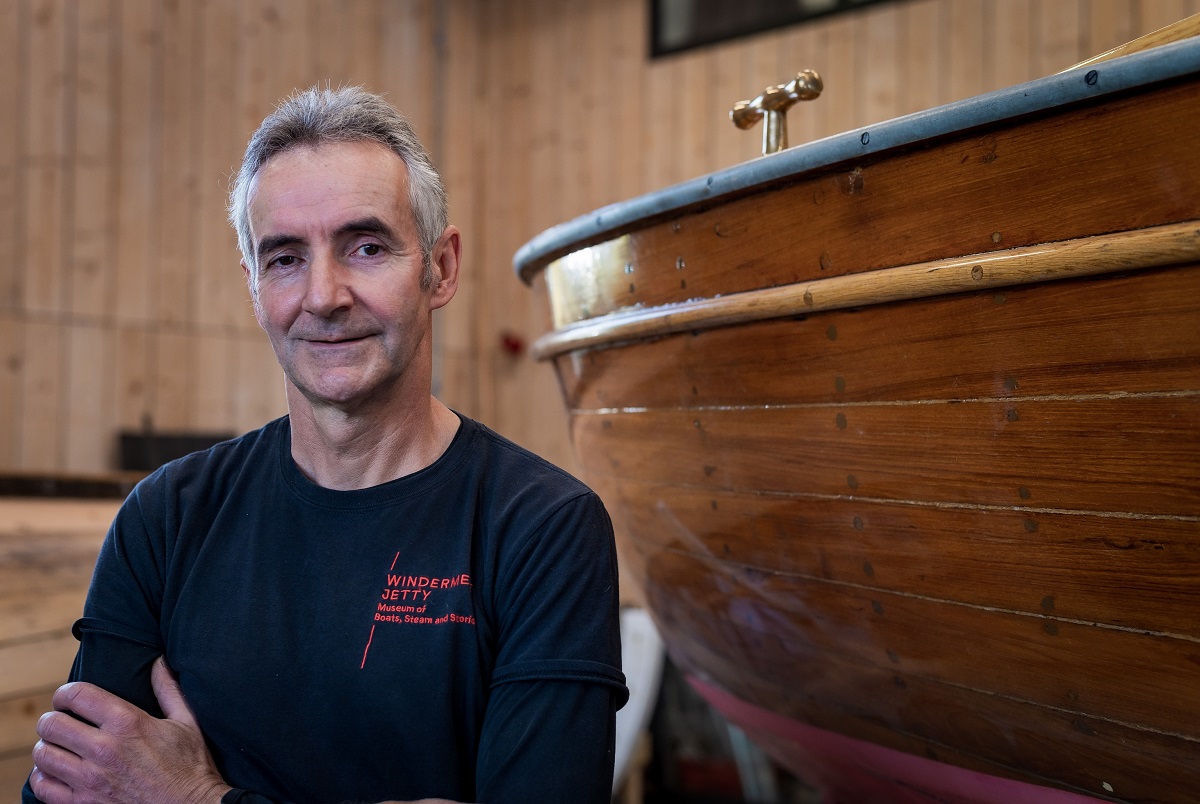 Man stood beside a wooden boat