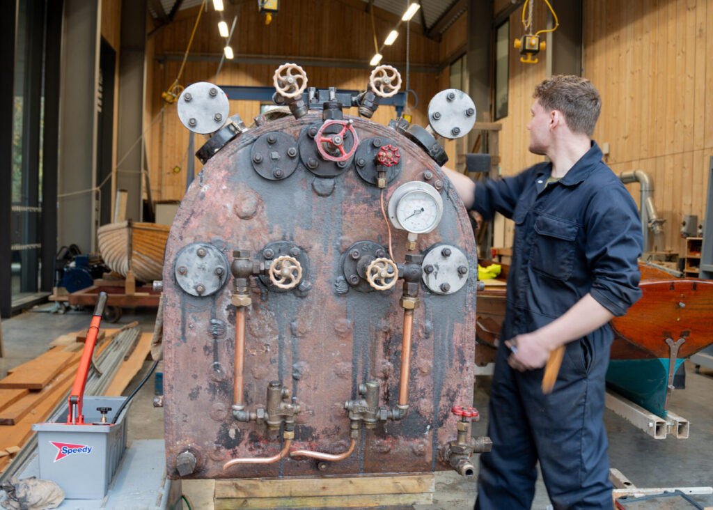 Finlay the apprentice working on steam launch Osprey's boiler