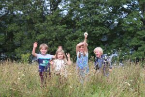 Group of children having fun in the meadow space at Windermere Jetty Museum.