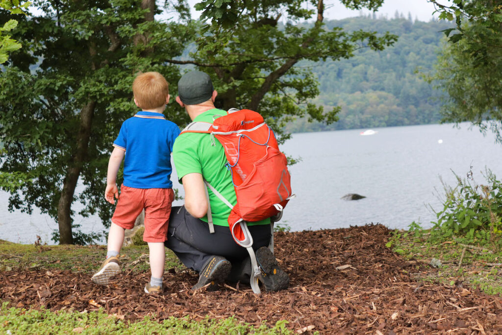 Father crouching next to his young son looking out on to the lake.