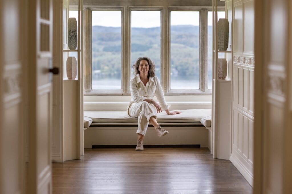 Artist Frances Priest sitting on the window seat in the White Drawing Room.
