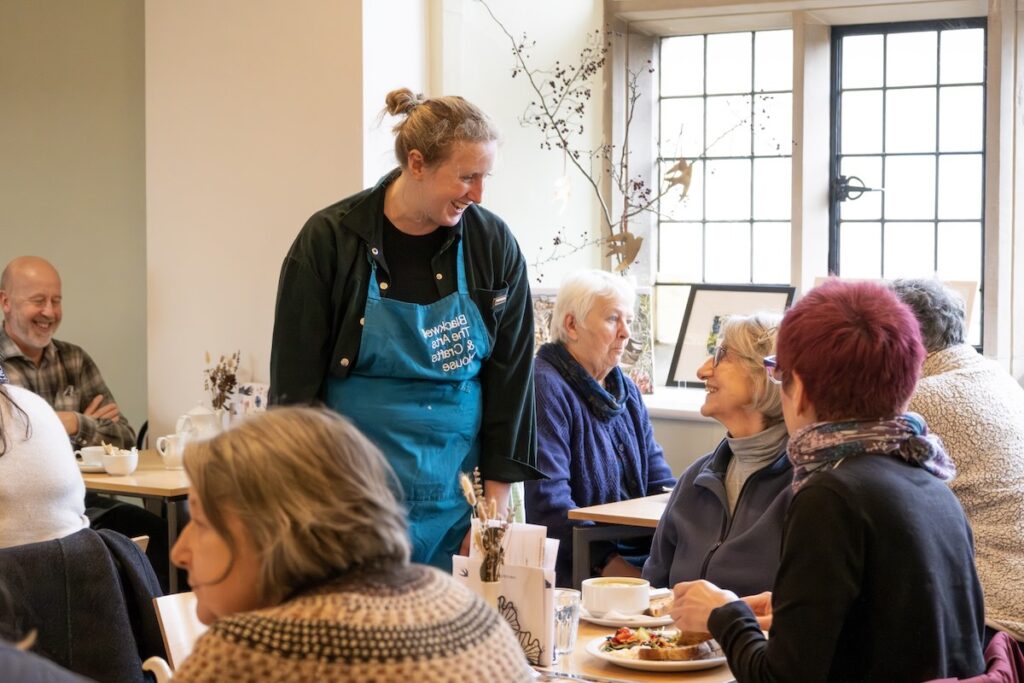 Happy member of staff chatting to visitors in the Blackwell Tea room.