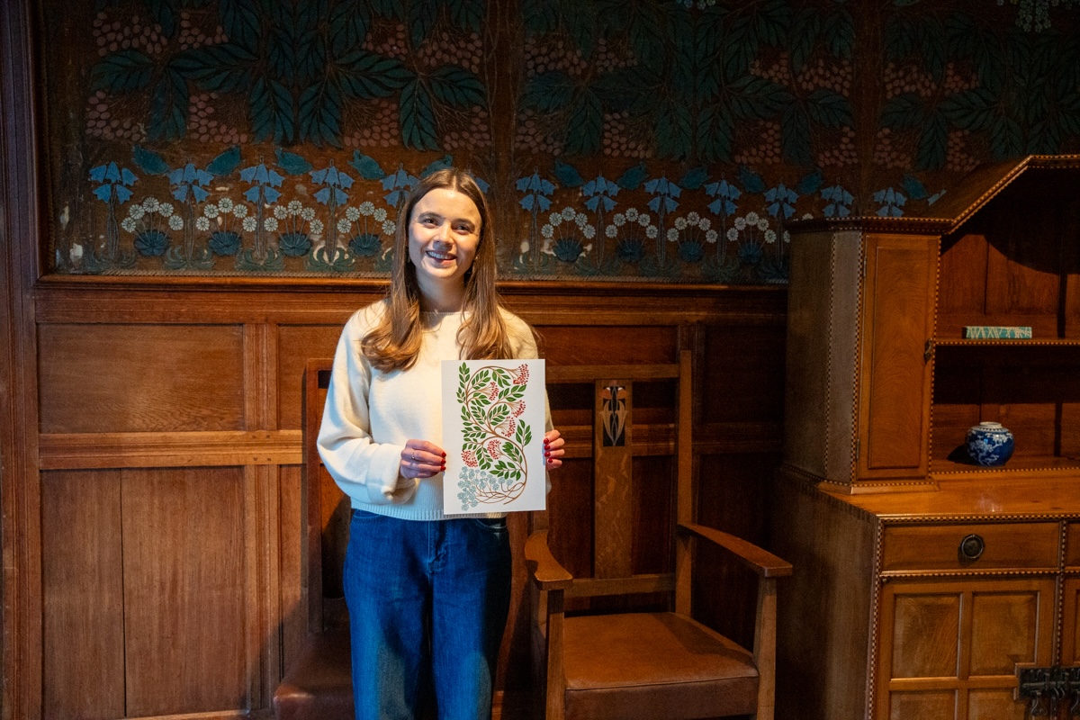 Tiana McInerney at Blackwell lo-res Credit Natasha Suriya from Lakeland Arts-058. Local artist Tiana McInerney happily holding her rowan berry inspired print in front of the hessian wall-covering in the Dining Room.