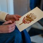 Close up of artist Tiana McInerney holding her print inspired by Blackwell's fire dogs in The White Drawing Room.