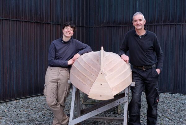 Senior Conservation Boat Builder Stephen Beresford and Homo Faber mentee Line Packer standing outside Windermere Jetty Museum with completed Windermere Skiff.
