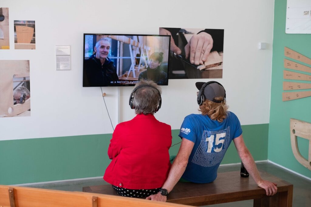 Two people watching the short film on show in the roomy Embodied exhibition.